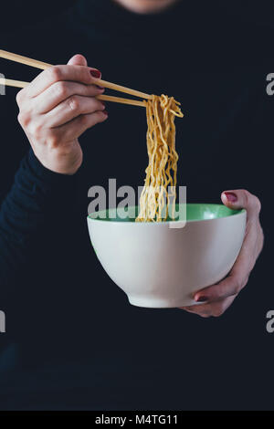 Woman holds a bowl of noodles with chopsticks Stock Photo