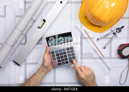 High Angle View Of Architect Hands Using Calculator Working On Blueprint Stock Photo