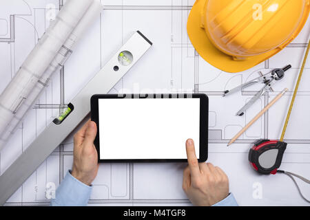 Close-up Of A Male Architect Touching The Screen Of Digital Tablet On Blueprint With Equipments Stock Photo