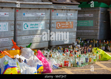 Overflowing glass bottle banks. A local authority glass recycling point is overflowing with glass & waste left by members of the public. Stock Photo
