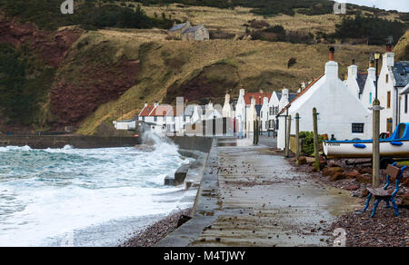 Pennan, Aberdeenshire, Scotland, UK. Large waves breaking on promenade and beached boat. Famous film location for movie Local Hero Stock Photo