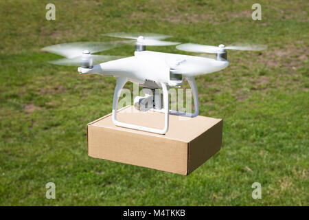 High angle view of drone carrying parcel over grassy field Stock Photo