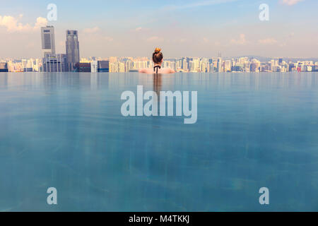 Woman Looking At Cityscape While Relaxing In Infinity Pool Stock Photo
