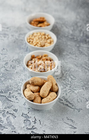Set of different types of nuts - peanuts in shells, pine nuts on gray background Stock Photo
