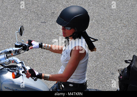 Female Sitting on Motorcycle with helmet and riding gloves Stock Photo