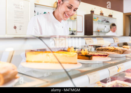 Women in pastry shop filling up sales display with pies Stock Photo