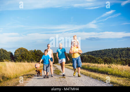 Family walking their dog on a dirt path Stock Photo