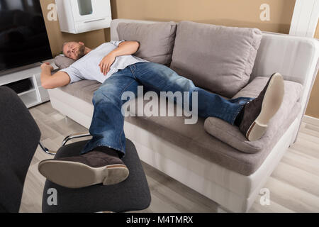 Young Man Sleeping On Couch In Living Room Stock Photo