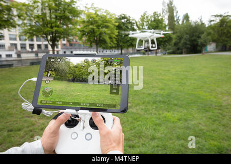 Man's Hand Operating The Quadrocopter In The Park Stock Photo