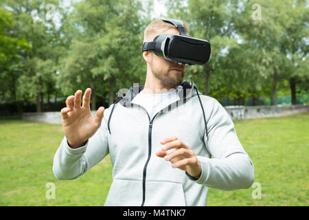 Close-up Of A Man Touching Something Using Virtual Reality Headset Glasses In The Park Stock Photo