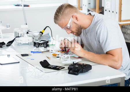 Close-up Of A Man Testing Electric Current Of Disassembled Drone Using Multimeter Tool Stock Photo