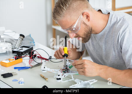 Man In Protective Glasses Fixing The Quadrocopter Drone On Table With Different Tools Stock Photo