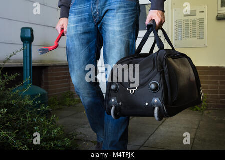 Close-up Of Male Robber With Crowbar And Steal Handbag From Home Stock Photo