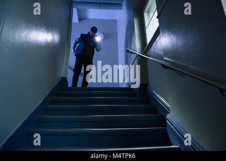 Male Security Guard Searching On Stairway With Flashlight Stock Photo