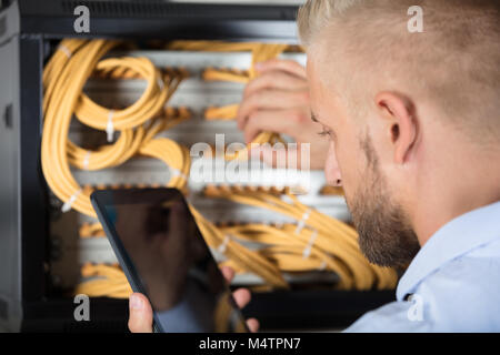 Male Technician Working On Server In The Data Center Using Cellphone Stock Photo