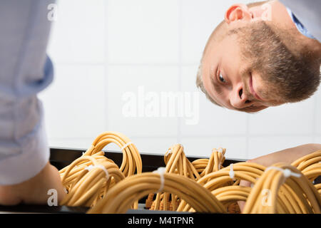 Male Technician Checking Cables In A Rack At Server Room Stock Photo