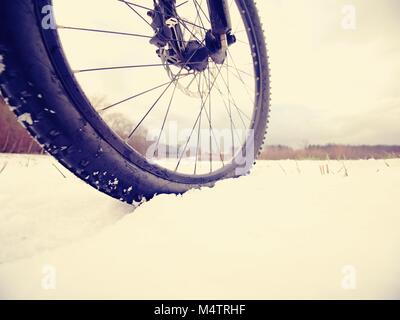 Winter mtb riding in snowy country. Low ankle view to wheel with snow mud tyre. Melting of snow flakes in tyre tread pattern. Stock Photo