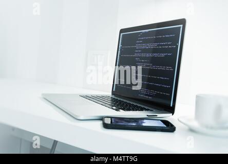 Web Application Developer Desk with Modern Laptop Computer and Website Source Code on Display. Mobile Work Concept. Stock Photo