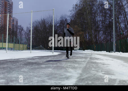 Image of athlete in black sports clothes running through winter Stock Photo