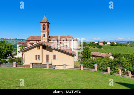 Small parish church on green lawn under blue sky in small town of Grinzane Cavour in Piedmont, Northern Italy. Stock Photo