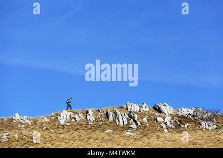 Young woman hiking on the mountain ridge with a panoramic view over the barren grass covered mountain landscape Stock Photo