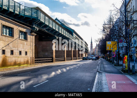 Berlin Prenzlauerberg, Eberswalder strasse U-2 railway station on elevated viaduct , cars on road,bike lane and shops. Stock Photo