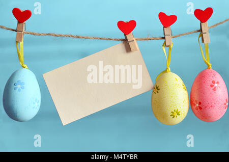 Easter eggs hanging on rope on blue wooden background Stock Photo