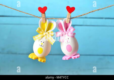 Easter eggs hanging on rope on blue wooden background Stock Photo