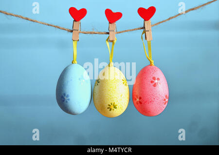 Easter eggs hanging on rope on blue wooden background Stock Photo