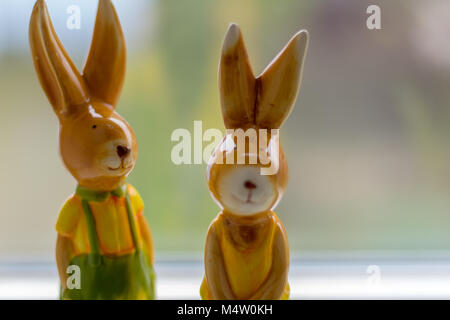two decoration rabbits stand near a window Stock Photo
