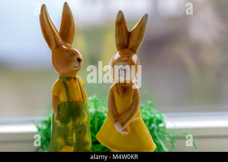 two decoration rabbits stand near a window Stock Photo