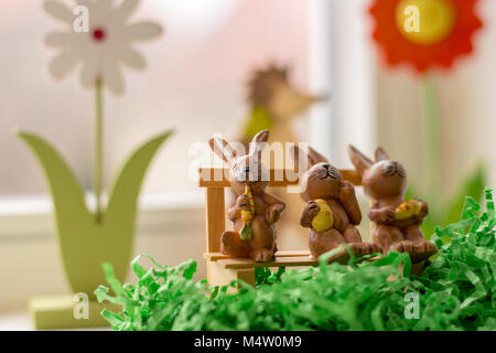 decoration rabbits sitting on a bench near a window Stock Photo