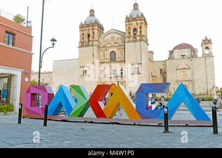 Colorful Oaxaca letters contrast with the iconic landmark Templo de Santo Domingo de Guzman in Oaxaca, Mexico. Stock Photo
