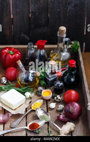Set of bottles with sauces, oil and vegetables in a woden box Stock Photo
