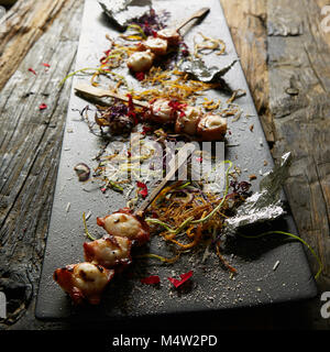 Snack from pieces of an octopus on a wooden skewer. Film effect Stock Photo