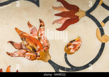 Semi-precious stones inlaid in white marble shape coral and gold flowers at the Taj Mahal in Agra, India. Stock Photo