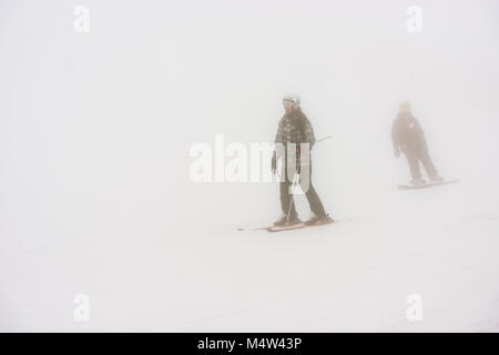Group of skiers glide down the slopes of the Sierra de Béjar ski resort - La Covatilla, Salamanca, Spain a day of strong blizzard and fog. Stock Photo