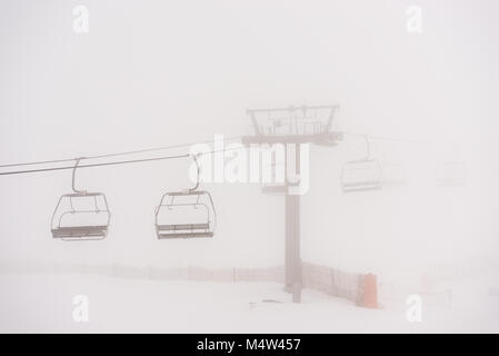 Empty chairlift on a day of blizzard and fog in the Sierra de Béjar ski resort - La Covatilla, Salamanca, Spain. Stock Photo