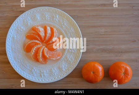 Mandarin oranges, one peeled and ready to eat on a plate, with copy space, Stock Photo