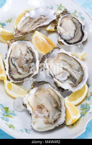 Plate with raw oysters and lemon slices on ice. Stock Photo