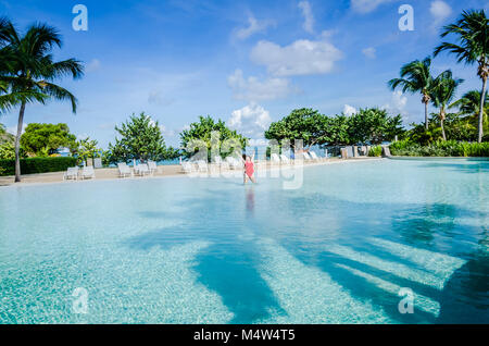 Woman in red swim suit jumps with excitement in one the largest pools in the Caribbean. Stock Photo