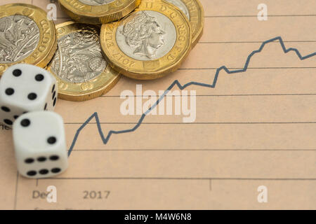 British pound coins and dice on a financial chart illustrate market risk and currency volatility, symbolizing uncertainty in UK economic trends. Stock Photo