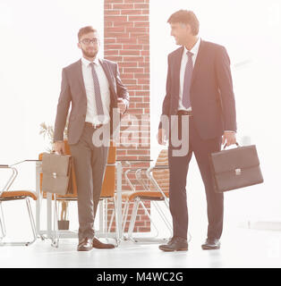 Two businessmen walking along in modern office building Stock Photo