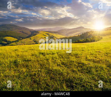 grassy meadow in mountains at sunset. beautiful summer countryside under the gorgeous sky Stock Photo