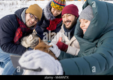 Portrait of two young couples taking selfie with dogs enjoying nice winter day outdoors Stock Photo