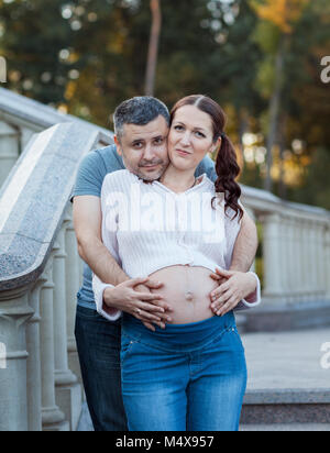 Young couple standing on the stairs. Young woman pregnant Stock Photo