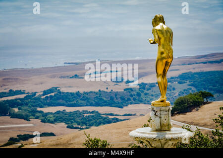 Golden girl statue at Hearst Castle looks over hills and ocean shoreline on California coast in San Simeon, CA. Stock Photo