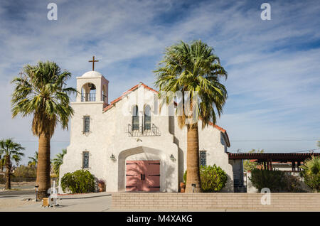 Pink and white Blessed Sacrament Church and School framed by date palm trees near Joshua Tree National Park and the Mojave Desert. Stock Photo