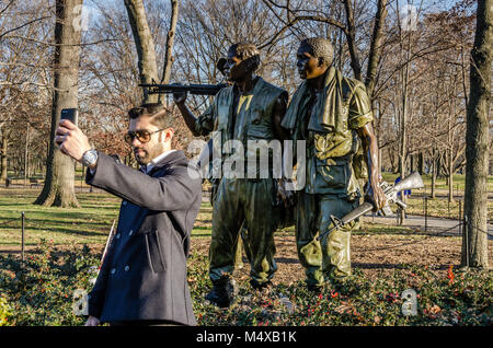 Tourist captures smartphone selfie with Three Soldiers Statue. The Three Soldiers is a bronze statue on the Washington, DC National Mall commemorating Stock Photo