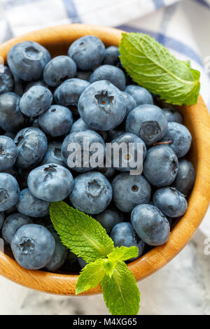 Ripe blueberries in a wooden bowl closeup. Stock Photo